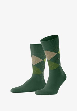 Green socks featuring an argyle pattern in varying shades of green and beige, with yellow stitching accents. Cotton blend fabric.