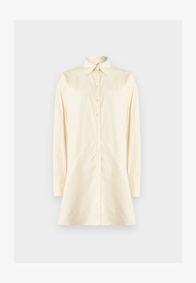 Kremas spalvos marškiniai su atverčiamu apykakliu, ilgomis rankovėmis ir praplatėjančia silueto linija; pagaminti iš lygaus audinio, su sagomis priekyje.