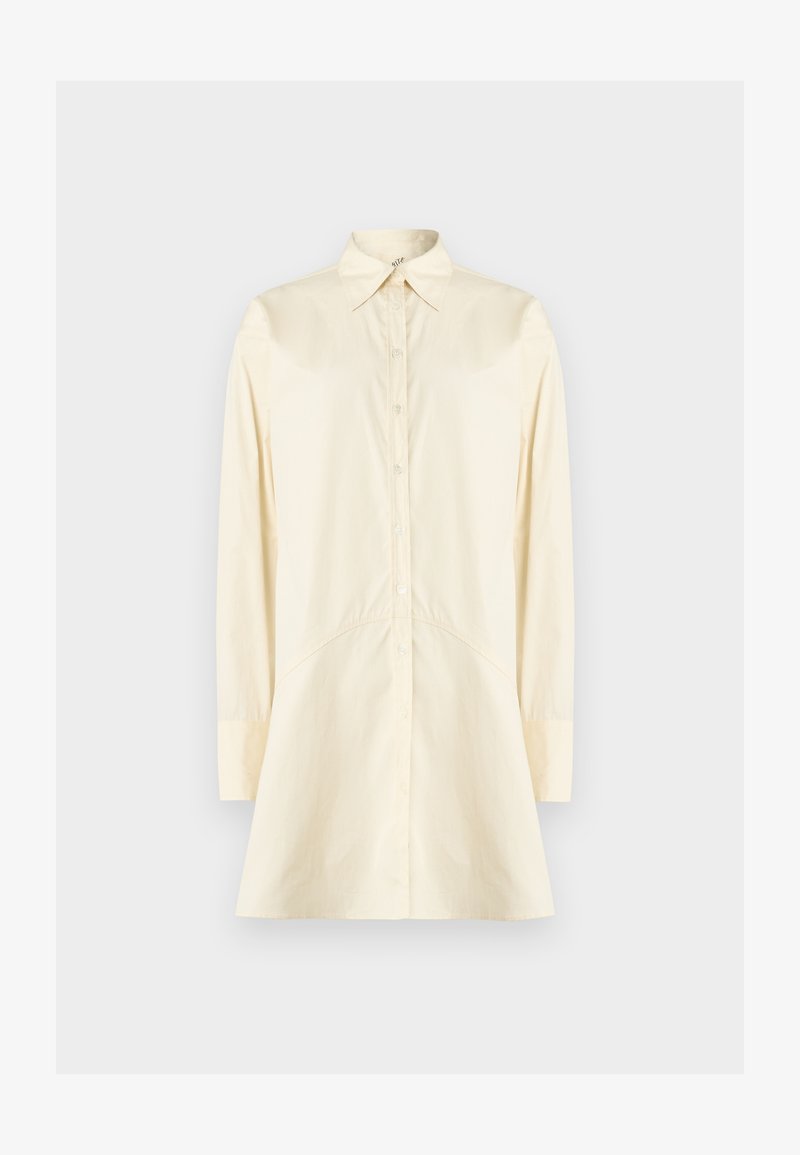 Chemise crème à boutons avec col pointu, manches longues et silhouette évasée ; fabriquée en tissu lisse, avec fermeture à boutons sur le devant.