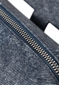 Denimtäschchen mit einem silbernen Reißverschluss, das aus einem strukturierten blauen Stoff besteht. Der Reißverschluss verläuft entlang der oberen Kante und hebt das funktionale Design hervor.