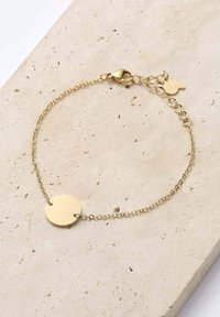 Bracciale in oro con pendente circolare. La catena è delicata, con chiusura a moschettone e lunghezza regolabile. Finitura liscia e lucida.