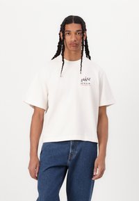 Cream-colored cotton t-shirt with short sleeves, featuring a graphic print of "HVAR CROATIA" and leaf design on the left chest.