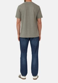 Gestreiftes kurzärmliges T-Shirt in gedämpftem Grün und Beige, kombiniert mit blauen Jeans. Das T-Shirt hat einen runden Ausschnitt und eine weiche Textur.