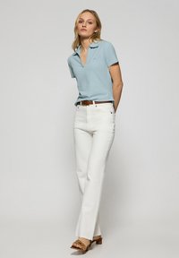 Ljusblå pikétröja med korta ärmar, vita högmidjade jeans och tanfärgade klacksandaler. Enkelt design, andningsbart tyg, skräddarsydd passform.