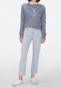 Modrý pletený svetr se strukturovaným vzorem, doplněný o světle modré rovné džíny a bílé tenisky. Jednoduchý, neformální outfit.