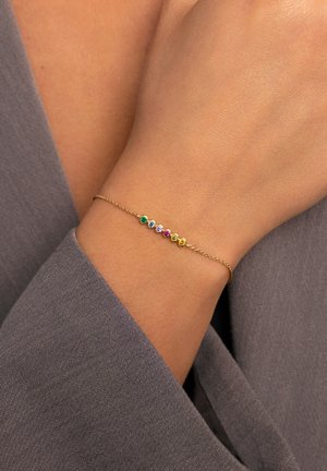 Pulsera de oro con cinco gemas de colores (verde, azul, púrpura, rosa, amarillo) engastadas en configuraciones circulares sobre una delicada cadena.
