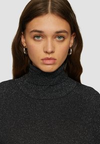 Schwarzer Rollkragenpullover mit gerippter Textur und metallischen Fadenakzenten. Besitzt einen eng anliegenden Ausschnitt und eine figurbetonte Passform.