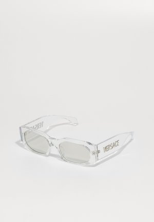 Clear plastic sunglasses with gray lenses, rectangular shape, embossed "Versace" logo on the temples, showcasing a modern design.