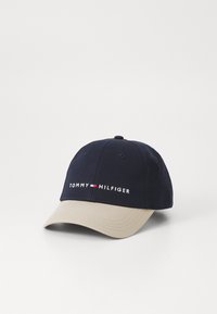 Marine bomuldscap med en beige skygge, med broderet "TOMMY HILFIGER" logo i hvidt og rødt. Seks-panel struktureret design.