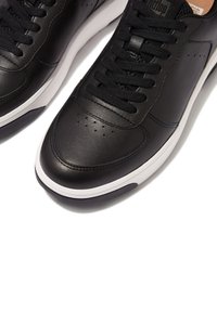 Schwarze Ledersneaker mit glatter Oberfläche, weißer Zwischensohle, schwarzen Schnürsenkeln und perforierten Details an der Zehenpartie zur Belüftung.