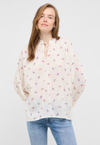 Blusa leggerissima e trasparente color crema con un motivo paisley rosso e blu. Presenta un collo annodato, una vestibilità ampia e maniche lunghe e gonfie.