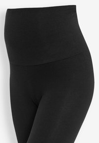 Fekete, magasderékú leggings rugalmas anyagból, sima textúrával és varrás nélküli kialakítással, amely jól simul a testhez.