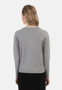 Pulover tricotat de culoare gri deschis, cu mâneci lungi, gât rotund și tiv bilat. Textură netedă cu detalii de cusături subtile și design ajustat.