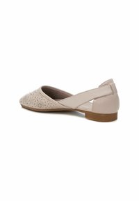Zapato plano beige con patrón floral recortado, puntera redonda y un bajo tacón marrón. Presenta un diseño de tiras cruzadas en la parte trasera.
