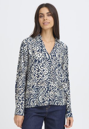 Langärmlige Bluse in Marineblau und Creme mit abstrakten Mustern. Verfügt über einen Kragen, eine Knopfleiste und eine lockere Passform. Glatte Stoffstruktur.