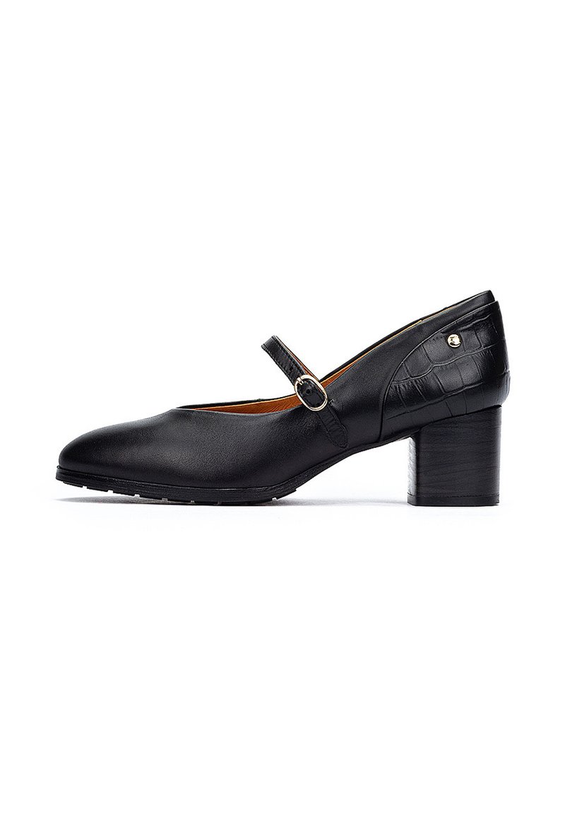 Chaussure Mary Jane en cuir noir avec un bout rond, une sangle de cheville avec une boucle ronde et un talon en bois de hauteur moyenne. Accents texturés sur le talon.