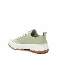 Zapatillas de lona verdes con cordones blancos, laterales texturizados y una suela blanca gruesa con una base de goma marrón. Forma redondeada y lengüeta.