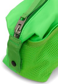 Grön nylonväska med en nätpanel på sidan, försedd med en metalldragkedja och en tygöglan för bärande. Slät yta med en mjuk och formbar form.