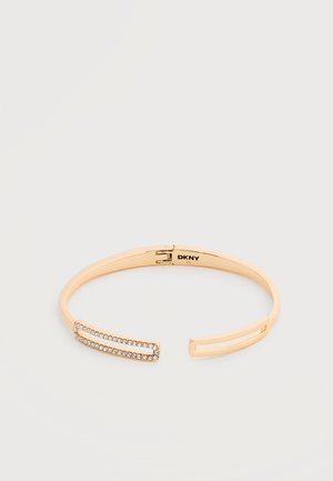 Brățară deschisă în ton auriu, cu accente de cristal dreptunghiular la un capăt și logo-ul DKNY în interior.
