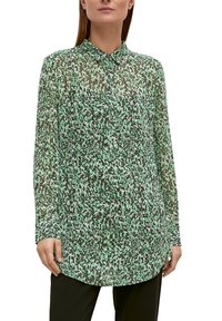 Camicia a maniche lunghe, con colletto, in tessuto verde trasparente con motivi astratti bianchi e verde scuro, caratterizzata da un orlo curvo e chiusura con bottoni.