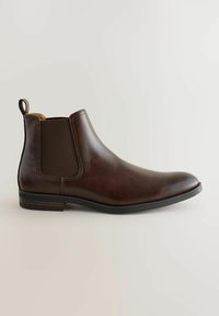 Bota Chelsea de cuero marrón con paneles laterales elásticos, punta redonda, suela de goma negra y una lengüeta en la parte posterior para facilitar su calzado.