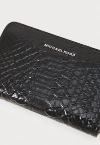 Black patent leather wallet with a crocodile texture. Features embossed pattern and silver "MICHAEL KORS" branding on the front.