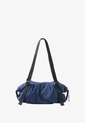 Sac d’épaule matelassé bleu avec sangles réglables noires et fermeture éclair, tissu doux avec détails froncés.