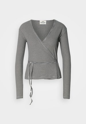 Langermet innpakket topp i svart og hvite striper, med v-hals, peplumkant og knyttedetalj i midjen. Myk tekstur.