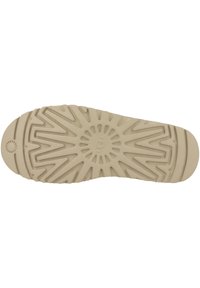 Suola di scarpa in gomma beige chiaro con un motivo di battistrada intricato che presenta linee radiali e un design circolare al centro.