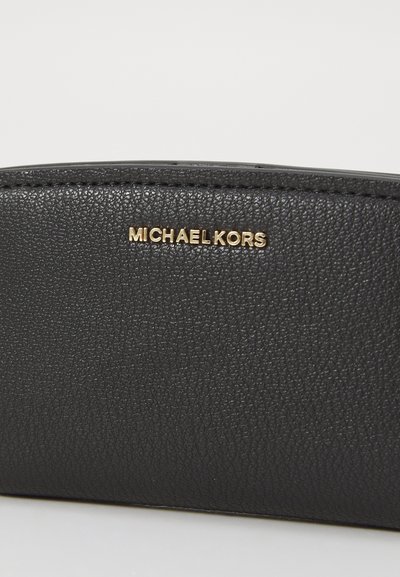Portefeuille en cuir texturé noir avec un logo doré "MICHAEL KORS". Le design est épuré avec des bords arrondis et des accents de couture visibles.