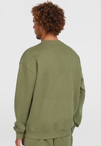 Grøn sweatshirt med afslappet pasform, rund hals og ribbede manchetter. Blød tekstur, med en ensfarvet og minimalistisk design.