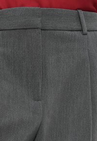 Szare, dopasowane spodnie o gładkiej teksturze, z płaskim przodem i bocznymi kieszeniami. Pas jest starannie wykończony, z szlufkami na pasek.