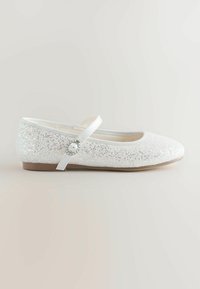 White glitter ballet flats with a rounded toe, elastic strap, and a decorative buckle. Smooth inner lining and flat rubber sole.