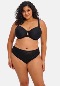 Černá vycpaná podprsenka s kosticemi a dekoltem ve tvaru klíčové dírky uprostřed. Ladící černé kalhotky s vysokým pasem a krajkovými detaily po stranách.