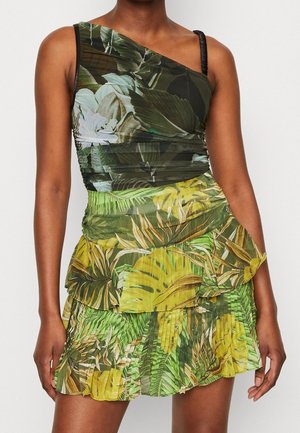 Robe asymétrique à motif de feuilles vertes et jaunes, ourlet à volants superposés, matière texturée avec un corsage ajusté.