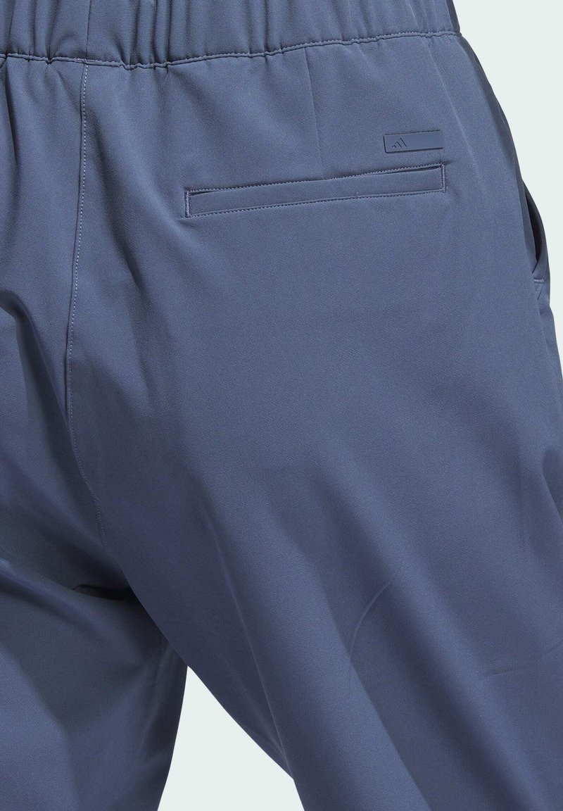 Pantalon bleu foncé en tissu doux, doté d'une ceinture élastique, de poches latérales et d'une poche arrière avec un détail de marque discret.