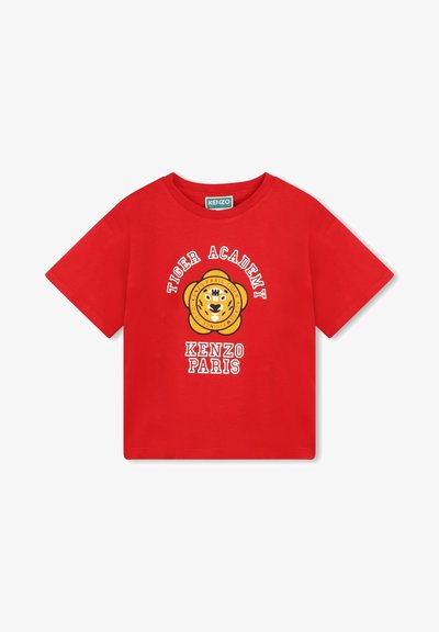 T-shirt en coton rouge avec un design graphique d'un tigre souriant entouré de fleurs, avec le texte "TIGER ACADEMY" et "KENZO PARIS" en dessous.