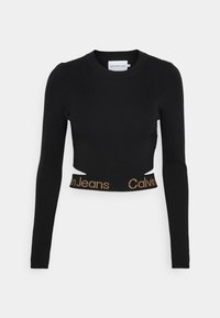 Svart långärmad crop top i ribbad trikå, med urklippta detaljer och ett brunt "Calvin Jeans" logoband.