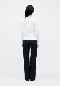 Svetlomodrý top s dlhým rukávom a okrúhlym výstrihom v kombinácii s čiernymi širokými nohavicami; hladká textúra, minimálny dizajn, bez viditeľných vzorov.