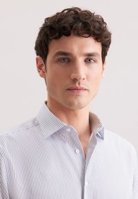 Camicia a righe button-up in azzurro chiaro e bianco, caratterizzata da un colletto classico e un design aderente, realizzata in tessuto liscio con una leggera lucentezza.