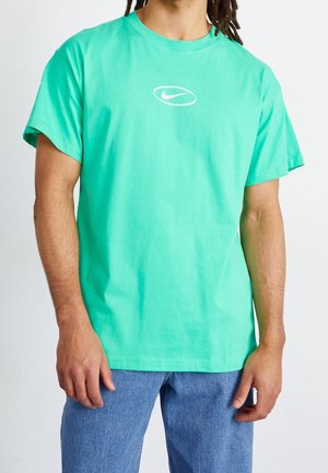 Miętowa bawełniana koszulka z krótkim rękawem i okrągłym dekoltem, z białym logo Nike na piersi. Nosić ze niebieskimi dżinsami.