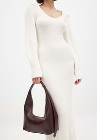 Valge ribaga kootud kleit pikkade varrukatega ja madala kaelusega, millele on juurde sobitatud tumepruun nahkne hobo-kott, millel on tõmblukk ja käepide.