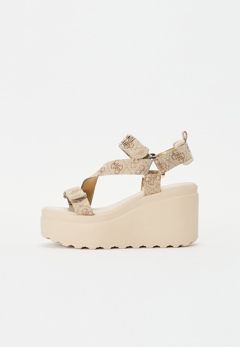 Plattform Sandalen mit einem beigen, strukturierten Obermaterial, überkreuzten Riemen und einer dicken, klobigen Keilsohle mit gerilltem Rand.
