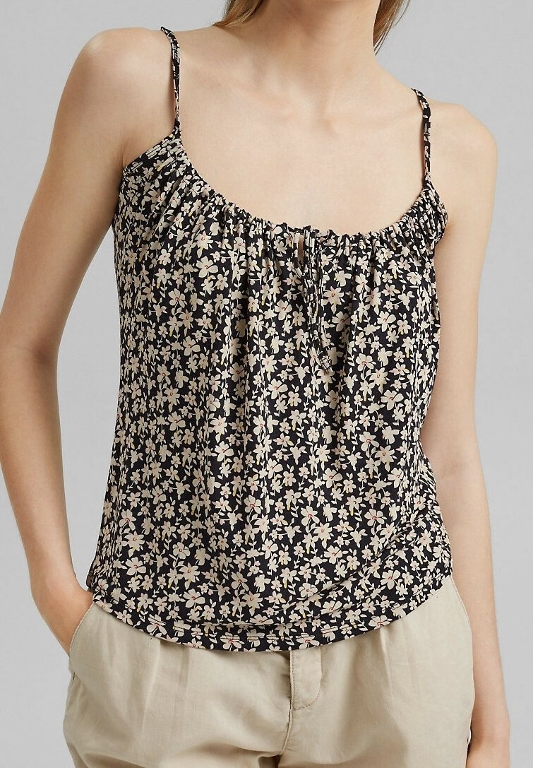 Haut noir à fleurs avec fines bretelles, présentant un col froncé et un motif floral crème et rose sur un tissu léger.