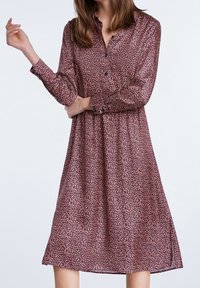 Robe à manches longues, boutonnée, en tissu bordeaux avec de petits motifs floraux roses et blancs, coupe décontractée avec des fentes sur les côtés.