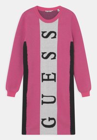 Abito lavorato a maglia con blocchi verticali in rosa, grigio e nero, con il testo "GUESS" ben in evidenza in nero su un pannello grigio.