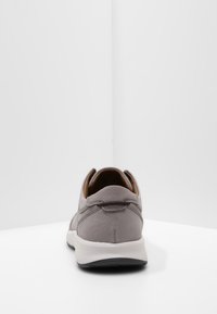 Baskets en daim gris avec une texture lisse, un arrière arrondi, une semelle intermédiaire blanche contrastante et une semelle extérieure noire. Design simple avec des accents minimalistes.