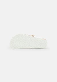 Schoenzool in wit rubber, getextureerd met een golfpatroon. Rondvorm met een lichte kromming bij de hak, minimalistisch ontwerp, geen zichtbare logo's.