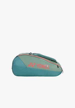 Sac de sport Yonex vert et bleu sarcelle avec logo rouge et fermeture éclair, conçu pour contenir des raquettes de badminton ou de tennis, posé à plat sur un fond blanc.