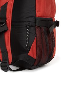 Mochila roja y negra con un exterior texturizado, que presenta un bolsillo de malla lateral, cremalleras y correas ajustables para un transporte seguro.